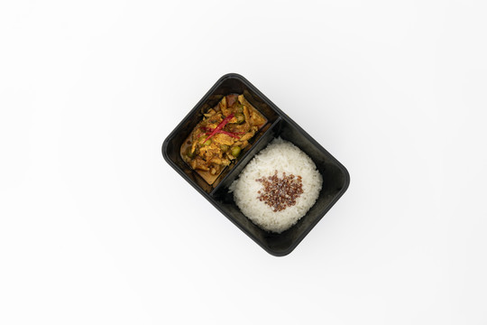 侧边有米饭的辣味咖喱猪肉俯视图，黑色盒子中有白色隔离物。