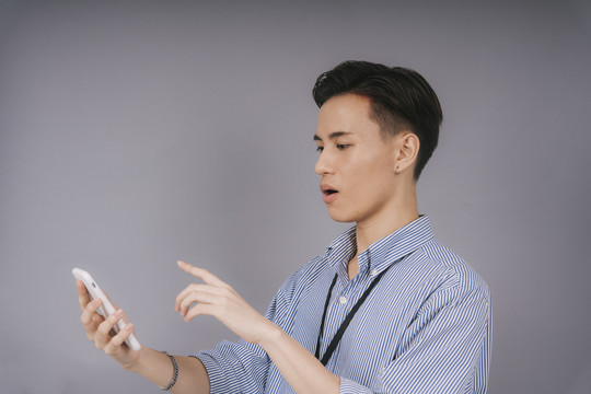 穿着蓝领衬衫的泰国帅哥商人在网上看到购物申请表上的销售信息后，感觉非常棒。