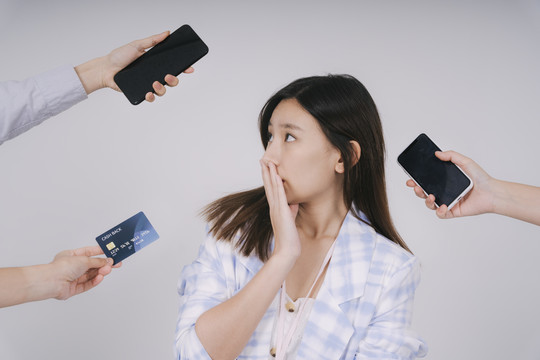 泰国美女对网上购物感到困惑。用智能手机和信用卡购物。隔离在白色背景上。