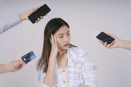泰国美女对网上购物感到困惑。用智能手机和信用卡购物。隔离在白色背景上。