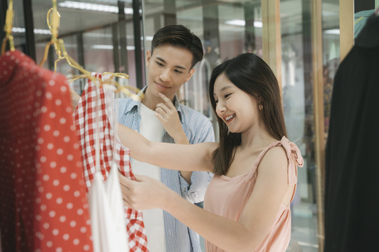一对亚洲年轻夫妇在室内时尚购物中心一起出去购物。