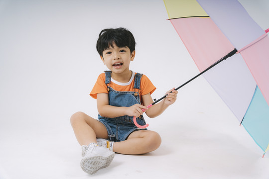 小男孩得到彩色粉彩雨伞时很高兴，他很喜欢雨伞。