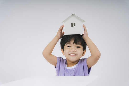 穿紫色t恤的小男孩在玩白色小房子。