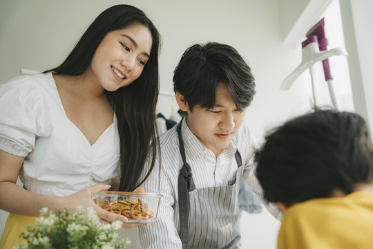 爸爸和妈妈早上上班前给儿子早餐麦片，妈妈给爸爸咖啡。