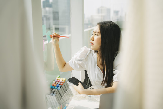 女设计师看了看她想用来做衣服的纺织品。她把她的想法写在窗户的便签上。