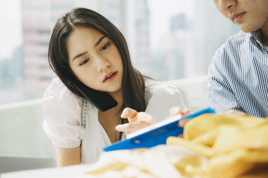 女设计师和她的男同事谈论布料的最新设计和想法，他们一起为这个项目选择纺织品。