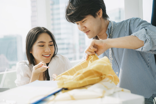 女设计师和她的男同事谈论布料的最新设计和想法，他们一起为这个项目选择纺织品。