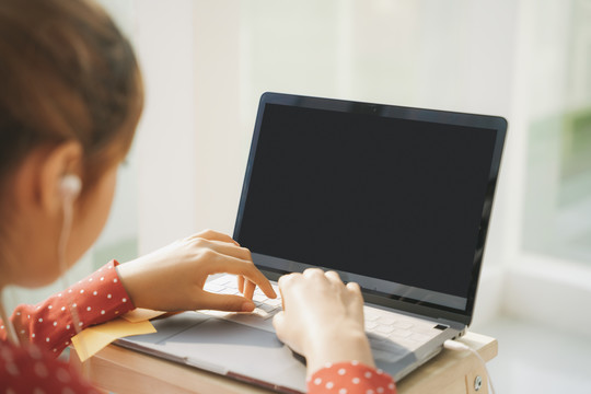 在家工作的概念-穿着红色睡衣衬衫的漂亮年轻女子在笔记本电脑上打字。检疫。