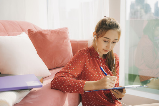 从家工作的概念-美丽的年轻女子穿着红色睡衣衬衫在家里工作的笔记本电脑，因为冠状病毒-19流行。检疫。