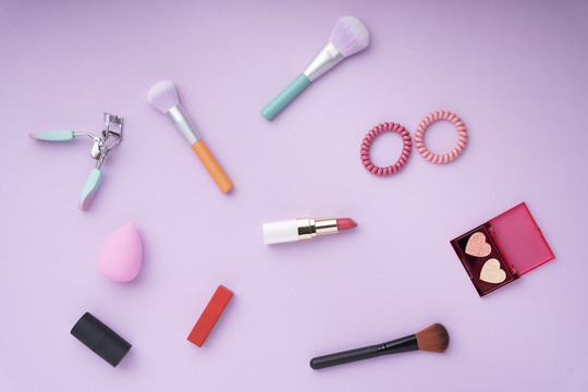 顶视图-紫粉色背景上的Colouful化妆品工具。