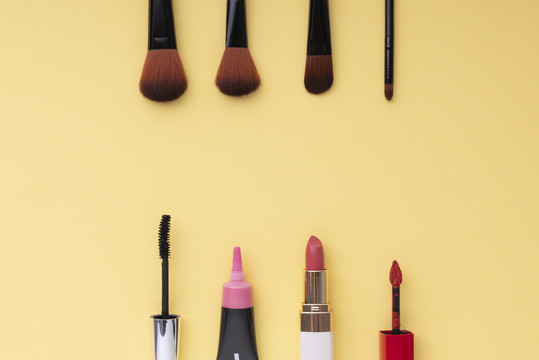 顶视图。平铺。化妆品化妆工具集合在明亮的黄色背景上。复制空间。