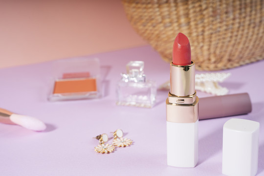 商业产品-红色唇膏瓶紫色地板与妇女配件。