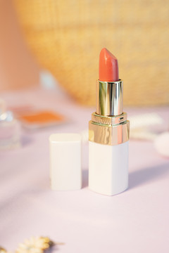商业产品-橙色色调唇膏在光泽白盒之上粉彩背景。