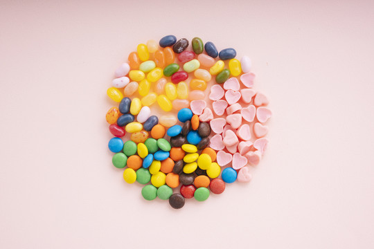 顶视图-粉红色背景上圆形彩色糖果的混合。