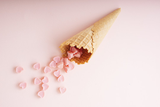 心形糖果，粉色背景上有华夫饼干冰淇淋筒。复制空间。