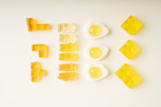 俯视图-许多黄色果冻在俄罗斯方块，熊，煎蛋，乐高形状的白色背景。