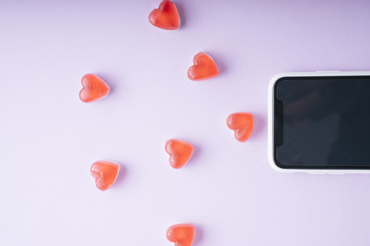 智能手机和wifi信号，紫色背景上有心形糖果-顶视图。