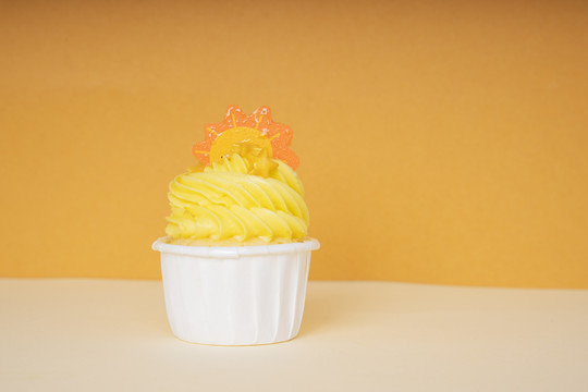 白色杯中的橙色纸杯蛋糕用一片橙色薄片装饰。复制空间。实体模型。