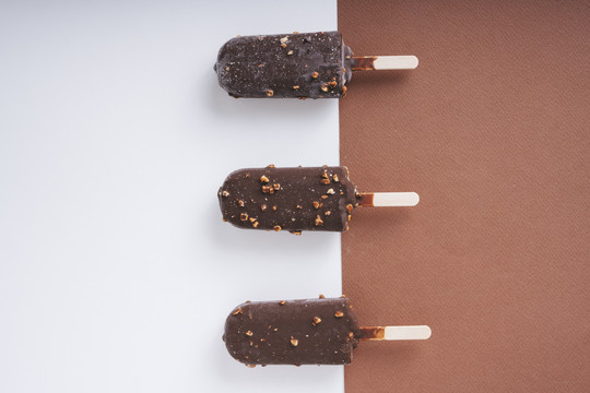顶视图-巧克力榛子冰淇淋棒上的白色和棕色背景。三个。