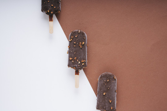 顶视图-巧克力榛子冰淇淋棒上的白色和棕色背景。三个。