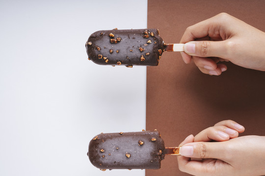 顶视图-巧克力榛子冰淇淋棒上的白色和棕色背景。两个。