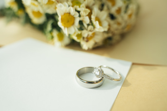 带有银戒指、纸和花的婚礼模型纸。复制空间。