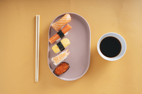 俯视图-日式寿司放在一个盘子里，上面放着绍玉酱油和剁碎棒。
