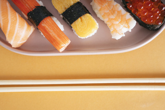 用筷子放在盘子上的日本寿司的俯视镜头。