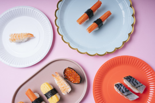 顶视图-日本寿司品种设置在盘子上粉红色背景。