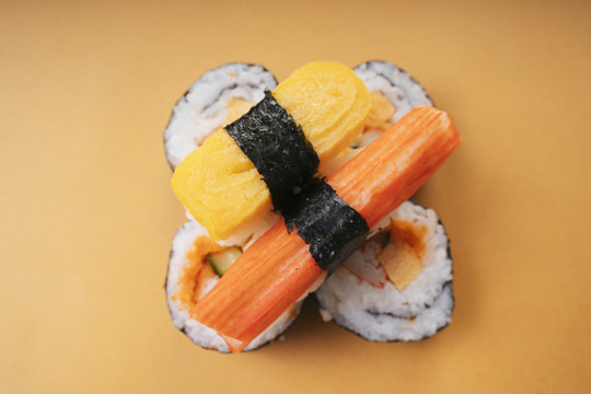 顶视图-蛋卷蟹棒寿司寿司寿司卷在黄色背景。