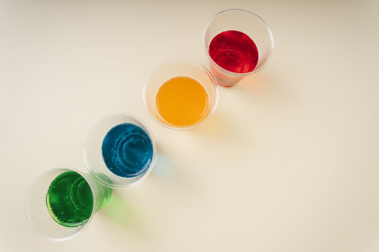 顶视图-甜彩虹苏打汽水在塑料杯与复制空间。绿色。蓝色。橙色。红色。