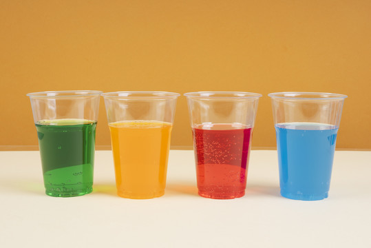 甜彩虹苏打起泡水在塑料杯复制空间。绿色。蓝色。橙色。红色。