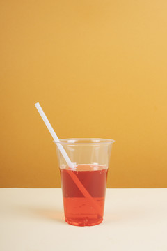 桌上放着吸管的塑料杯里的红色起泡水。