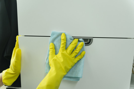 手戴黄色手套用抹布清洁家具。Covid-19冠状病毒预防。
