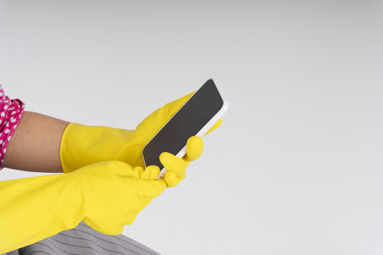 清洁工女佣戴着黄色防护手套拿着智能手机留着复印空间。应用服务。