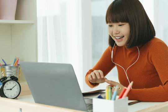 美丽的年轻亚泰黑人短发女子学习从家里学习在线笔记本电脑和戴耳机。