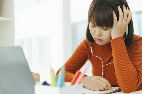 美丽的年轻亚泰黑人短发女子学习从家里学习在线笔记本电脑和戴耳机。紧张和无聊的表情。