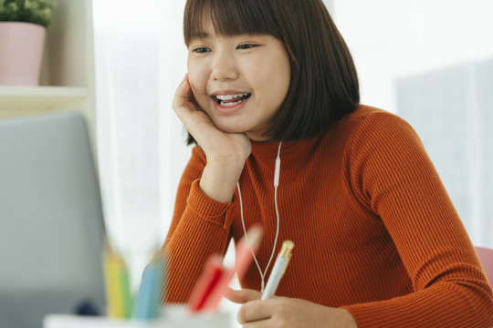 美丽的年轻亚泰裔黑色短发女子在家学习时用笔记本电脑和朋友聊天。