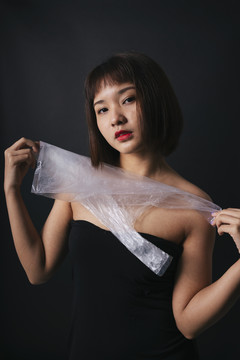塑料时尚概念。美丽的亚泰妇女短发塑料袋隔离黑色背景。