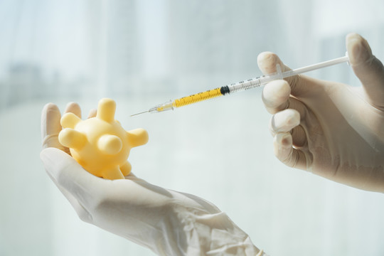 戴手套的科学家医生将疫苗注射到covid-19病毒中。