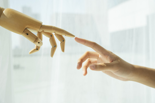 木制半机器人的手和人类的手互相伸出。