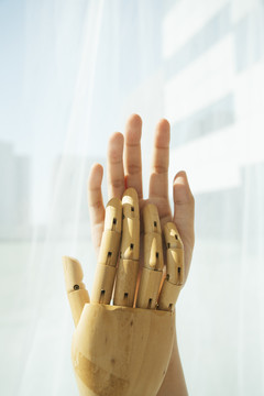 木制半械人机器人的手和人互相接触。