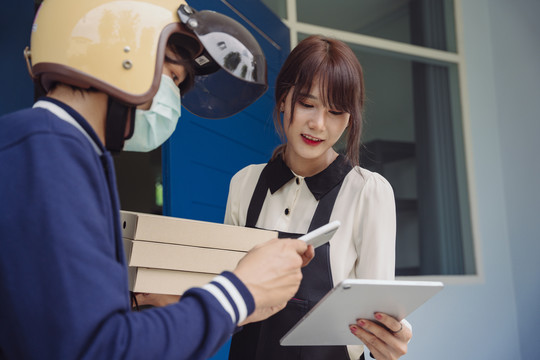 一位亚洲妇女在笔记本电脑上用应用程序扫描代码检查订单并支付比萨饼的费用。网上银行服务。提供食物。