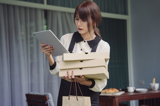 美丽的亚洲女人在家里用笔记本电脑在线订购比萨饼。新常态。