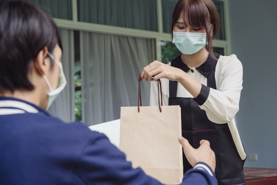 亚泰女性从网上申请购买物品。送货员把东西送到她家里。