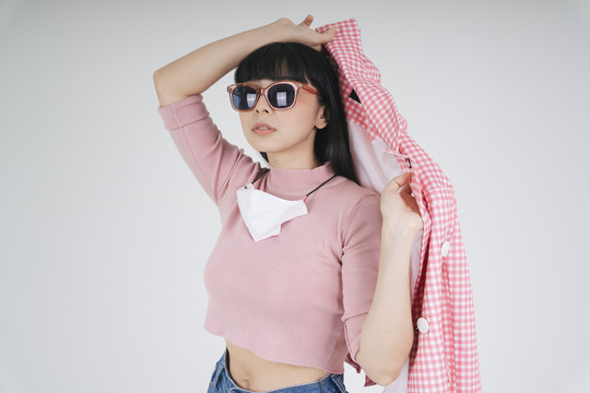 时尚写真-美丽的亚泰黑色长发女子穿着粉色夹克，戴着白色背景的太阳镜。