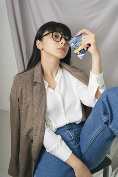 特写-美丽的亚泰黑发女子戴着眼镜拿着信用卡银行。时尚肖像。