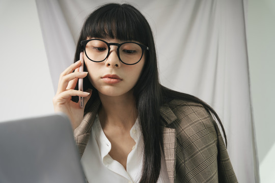 商务亚泰长黑发女子戴眼镜用笔记本电脑。在家工作的概念。
