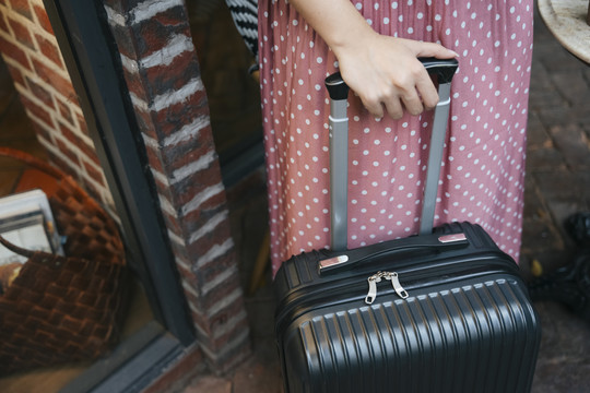 街上一个穿着粉色连衣裙，背着旅行包的女人。旅游理念。