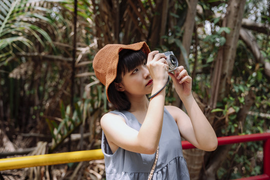 年轻的泰国亚裔女游客在乡间小路上带着老式相机。本地旅行。